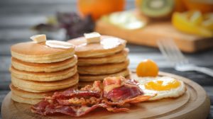 Tasty breakfast with pancakes, fried egg and bacon on wooden board | Fathers Day Recipes To Spoil Dad With | Featured