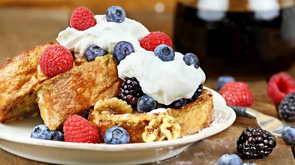 Delicious golden french toast with fresh blackberries, raspberries, blueberries, powdered sugar and whipped cream | French Toast Recipes | A Collection Of The Best Homemade Recipes