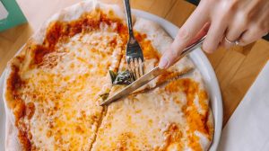 _hM6B5ApADU-person slicing pizza using knife and fork-homemade pizza recipes-us-feature