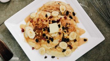 7hlOjB5VVb0-plate of pancake topped with sliced bananas and chocolate syrup-Healthy Banana Pancake Recipe-us-feature