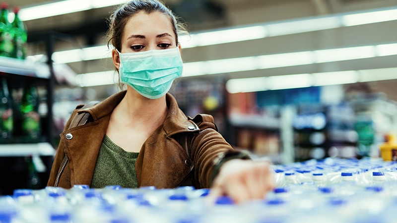 Young woman wearing protective mask on her face and shopping purified water | Stock-Up Grocery List And Recipes To Cook For Coronavirus Quarantine | Staple food