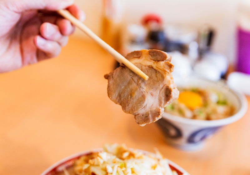 hand holding chashu by chopsticks tonkotsu | best instant ramen recipe