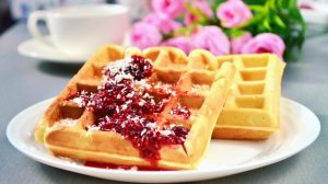 Sweet Waffles topped with Warm Raspberry Sauce and a white cup of coffee | Delicious Coconut Flour Waffles You Can Make For Quarantine | coconut flour recipes | Featured