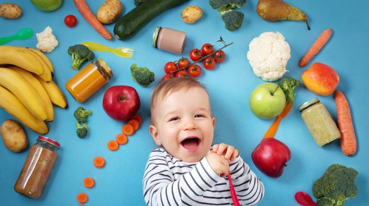 Baby surrounded with fruits and vegetables on blue blanket | Healthy Recipes For Toddlers 12-18 Months | baby food recipes | featured