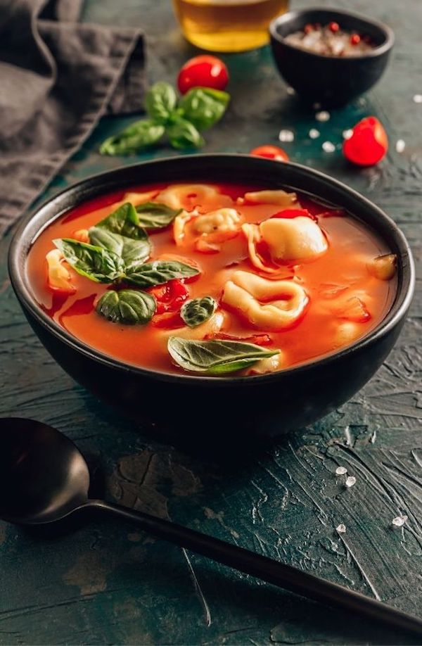 Tomato soup with tortellini in black bowl on dark background | super easy slow cooker recipes