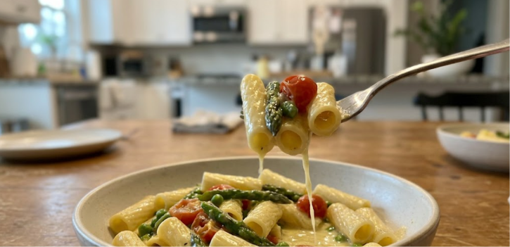 Easy pasta primavera in a white bowl with asparagus, cherry tomatoes, peas, and rigatoni in a light cream-lemon sauce.